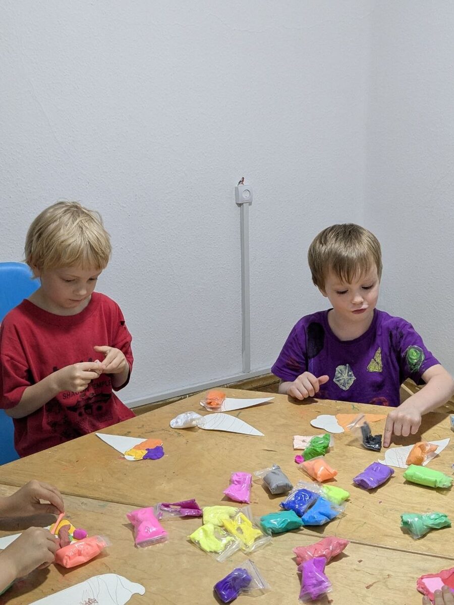 ბავშვები ფერად პლასტილინს ძერწავენ მაგიდასთან Kids Space-ში